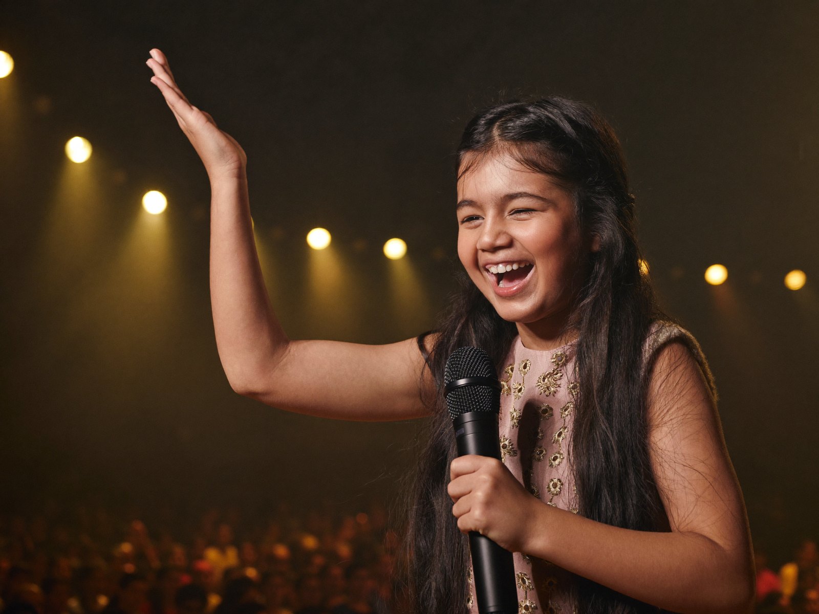 A young Indian girl sings into a microphone at a music recital.